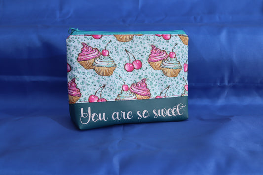 Kosmetiktasche mit gezeichneten Cupcakes in Mint und Pink, handgemacht mit türkisfarbenem Reißverschluss. You are so sweet steht in Schönschrift auf dem petrolfarbenem Kunstleder

