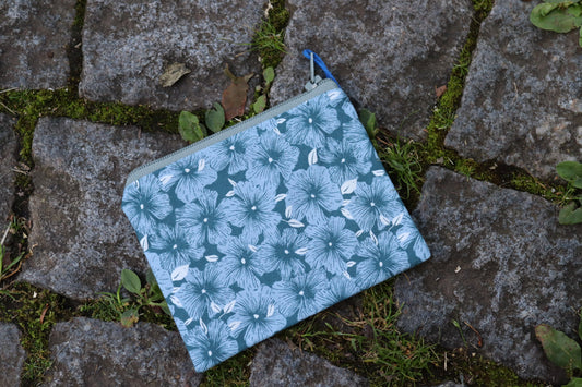 Handgenähtes Täschchen aus blauem Stoff mit hellblauen Blumenmotiven und oliv-farbenen Reißverschluss – ideal für Karten, Kleingeld oder kleine Utensilien.​