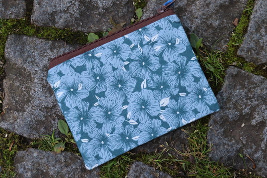 Handgenähtes Täschchen aus blauem Stoff mit hellblauen Blumenmotiven und braunem Reißverschluss – ideal für Karten, Kleingeld oder kleine Utensilien.​