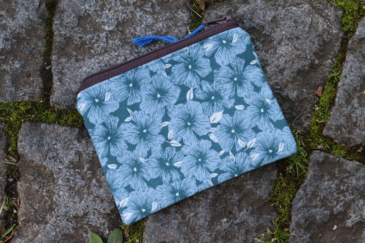Handgenähtes Täschchen aus blauem Stoff mit hellblauen Blumenmotiven und dunkelbraunem Reißverschluss – ideal für Karten, Kleingeld oder kleine Utensilien.​