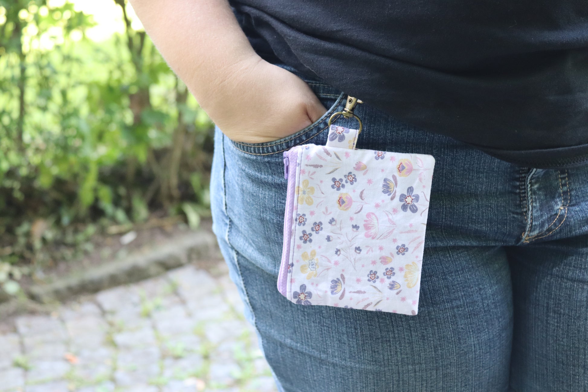 Handgenähtes Täschchen mit lila Blumenmuster und Karabiner – kompakt und stilvoll für unterwegs.