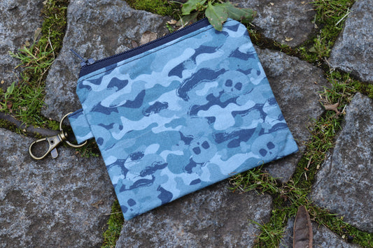 Handgenähtes Täschchen mit blauem Camouflage-Muster und kleinen Totenkopf-Motiven – robust und individuell.