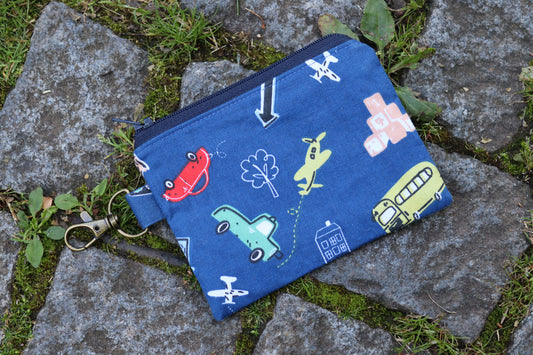 Handgemachtes Stofftäschchen mit Reißverschluss, genäht aus dunkelblauem Baumwollstoff mit niedlichem Fahrzeug-Muster. Autos, Busse und Flugzeuge in sanften, pastelligen Farben.